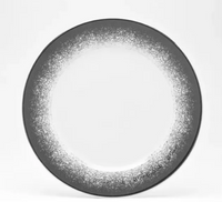 The Poc A Poc Platinum Edge is a round handcrafted dinnerware plate featuring a white center and a dark gray, speckled rim that blends in a gradient toward the middle.
