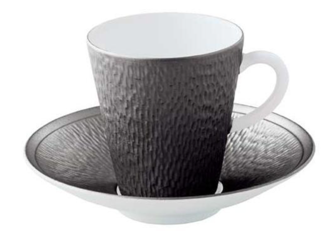 The Raynaud Mineral Irise Dinnerware Dark Grey cup and saucer set features a textured dimpled pattern that fades from dark exterior to light interior, with a handle, crafted in France.