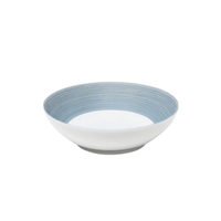 A shallow, round ceramic bowl from the JL Coquet Hemisphere Dinnerware Storm Blue collection, featuring a white exterior and interior with light blue concentric lines near the rim, set against a plain white background.