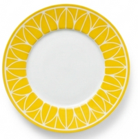 The Christofle Malmaison Riviera Dinnerware features a white plate with a bright yellow geometric rim, echoing lemon slices. Its plain center evokes elegant French Riviera dining.