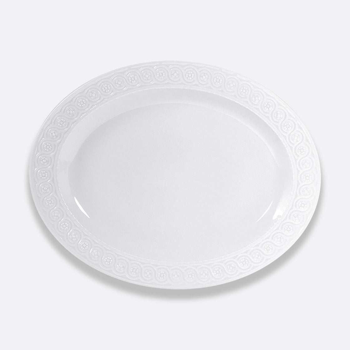 The Bernardaud Louvre Dinnerware features a plain white oval ceramic plate with a subtle decorative rim pattern inspired by Renaissance elegance, shown against a light gray background.