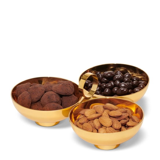 The Sintra 3-Bowl Server by Aerin features three gleaming gold bowls joined by a central handle, beautifully displaying chocolate truffles, chocolate-covered nuts, and whole almonds against a white background.