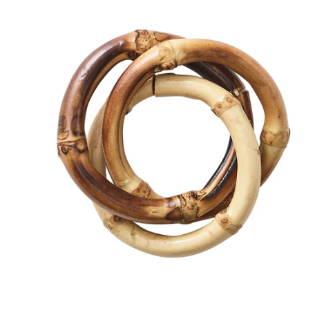 The Bamboo Trinity Napkin Ring Set of 4 by Kim Seybert features three interlocked bamboo rings in varied brown tones, offering a stylish, sustainable accent for any dining table.