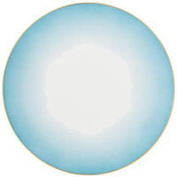 The Aura Dinnerware by Raynaud is a round white plate with a light blue gradient border, concentric lines, and a delicate gold rim. Its modern minimalistic design reflects contemporary style influences.