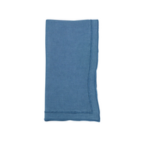 A single blue Overlock Stonewash Border Napkin by Saro Trading, neatly folded with slightly frayed edges, is displayed on a white background.