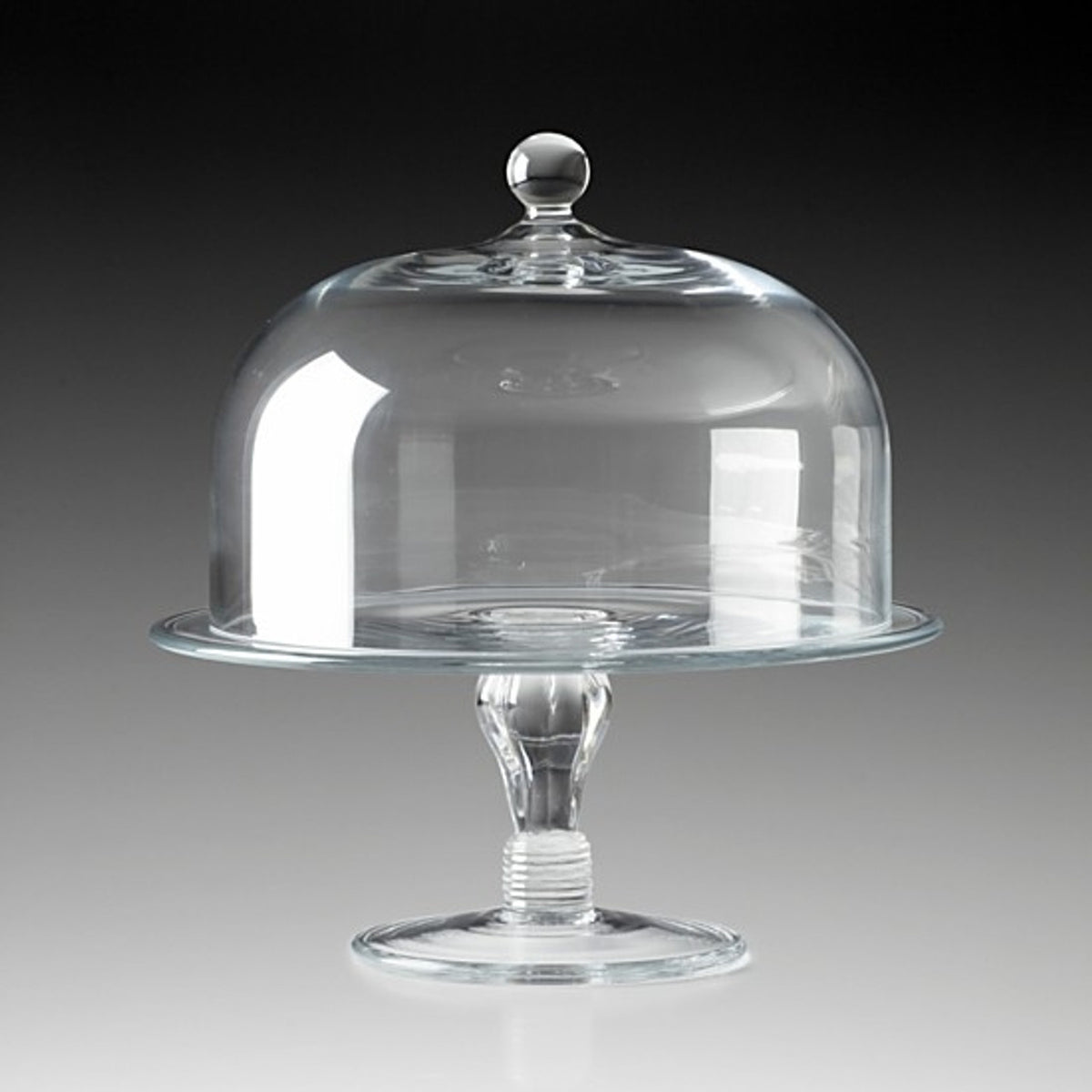 The William Yeoward Classic Cake Dome 11″ is an elegant cake display, featuring a clear round base and a matching antique-inspired dome cover, both expertly crafted from handmade crystal glass and shown against a gray to black gradient background.