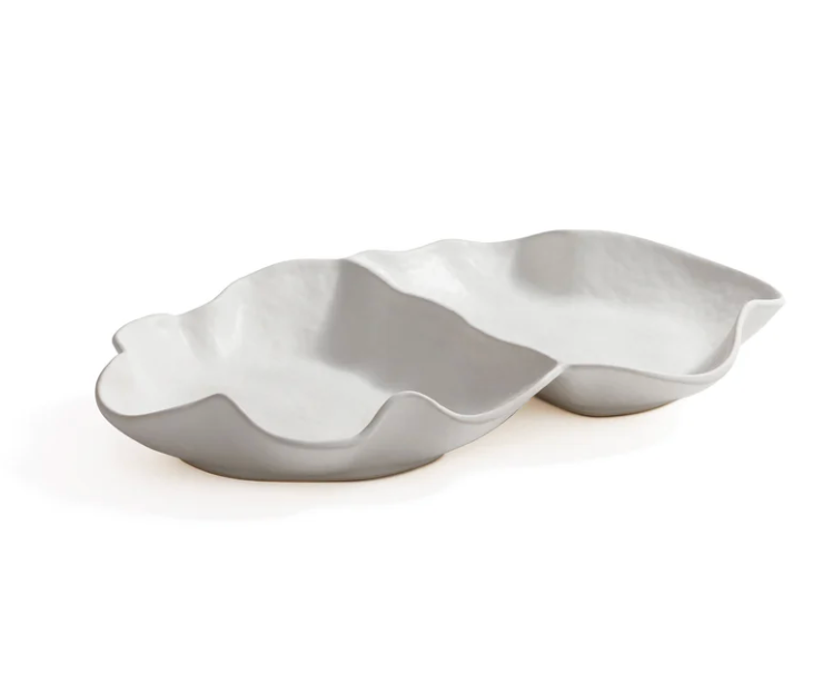 The Zodax Alto Two Section Ceramic Serving Bowl features a modern, sculptural matte white design with two connected, irregular compartments, resembling abstract leaf or shell forms.