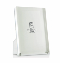 A minimalist Tizo Lucite Clear Frame stands upright on a white surface, with the text CH CURRENT HOME displayed on the insert inside this floating acrylic picture frame.