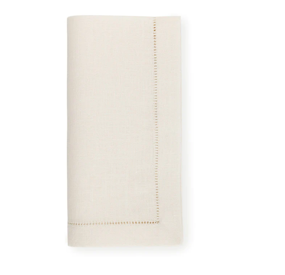A set of four ivory Sferra Festival napkins, each crafted from fine European linen and featuring a decorative stitched border.
