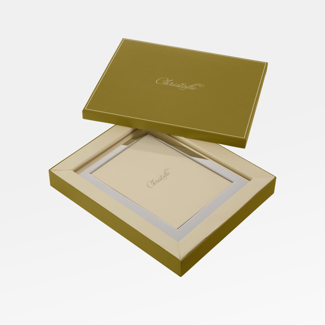A gold Christofle gift box, lid slightly open, reveals a Fidelio Christofle Silver Plated Frame 7x9.5 inside. The Christofle logo appears on both the gift box lid and the elegant silver-plated frame.