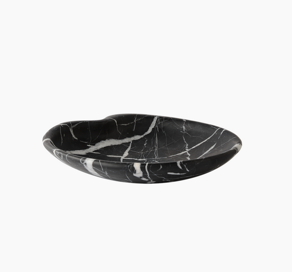 The Lily Marble Bowl Black by Greg Natale features natural black marble with white veining, a shallow rounded shape, and a slight dip on one side, shown against a plain white background.
