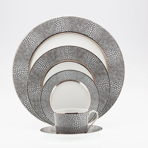 The Makassar Gray & Platinum Dinnerware by Royal Limoges/Bia Cordon Bleu, handmade in France, includes four nesting plates and a teacup with saucer, featuring a textured gray and white circular pattern, elegantly displayed upright.