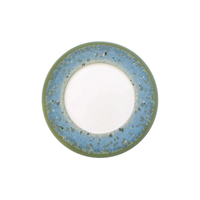 Top view of a round Jaune De Chrome Nymphea Dinnerware plate, made in France, featuring a wide textured blue and green rim with a plain white center on a white background.