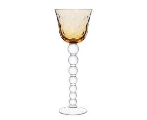 The Bubbles Hock Stemware by Saint-Louis features an amber dimpled bowl, a clear stem of stacked glass spheres, and a flat base—a striking design inspired by contemporary Saint-Louis crystal tableware.