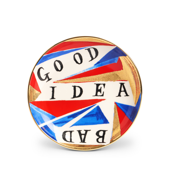 The Good/ - Bad Idea Plate by Ruan Hoffmann for L’Objet features abstract red, blue, and gold geometric shapes with “GOOD IDEA BAD” boldly inscribed across its earthenware surface.