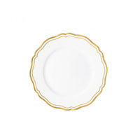 The Raynaud Polka Gold Dinnerware features a white porcelain plate with a scalloped edge and decorative gold trim on the rim, creating an elegant look on a simple white background.