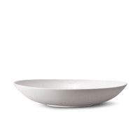 A smooth, round, shallow white ceramic bowl from L'Objet's Terra Stone Dinnerware collection, shown in profile on a white background.