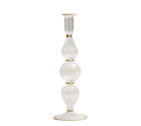 The Ripple Candle Holder - Clear by Kim Seybert is a tall, hand-blown glass candlestick holder with gold accents and a ribbed texture. It features three distinct rounded and elongated sections stacked vertically, offering a refined touch of iridescent luster.
