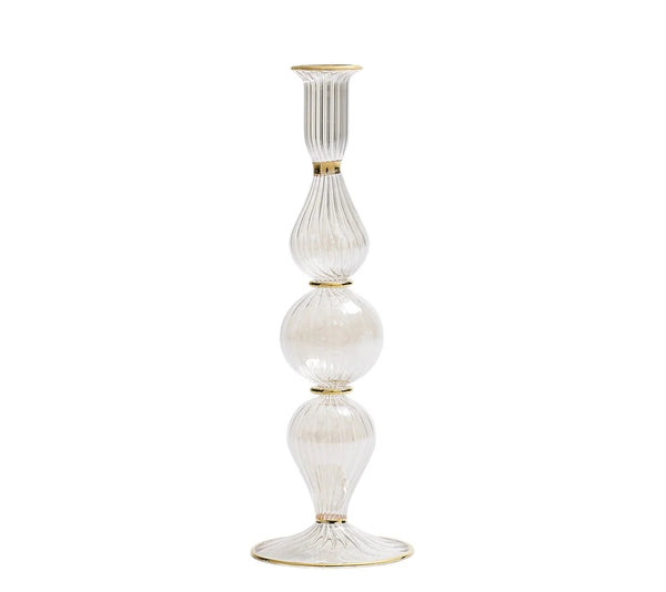 The Ripple Candle Holder - Clear by Kim Seybert is a tall, hand-blown glass candlestick holder with gold accents and a ribbed texture. It features three distinct rounded and elongated sections stacked vertically, offering a refined touch of iridescent luster.