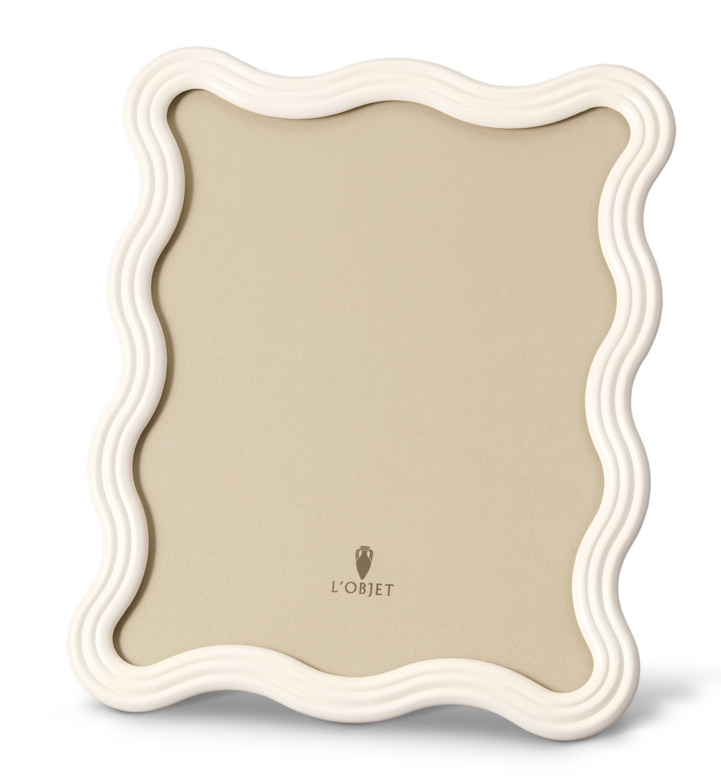 The Ripple Enamel Frame White by L'Objet is a handcrafted Portugal frame with a glossy, wavy border, beige background, modern sculptural design, and the L'Objet logo at the bottom center.