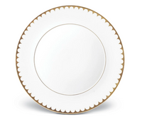 The L'Objet Aegean Filet Gold Dinnerware plate is crafted from fine white porcelain with a gold scalloped border and a thin 24k gold inner ring, set against a classic white background.