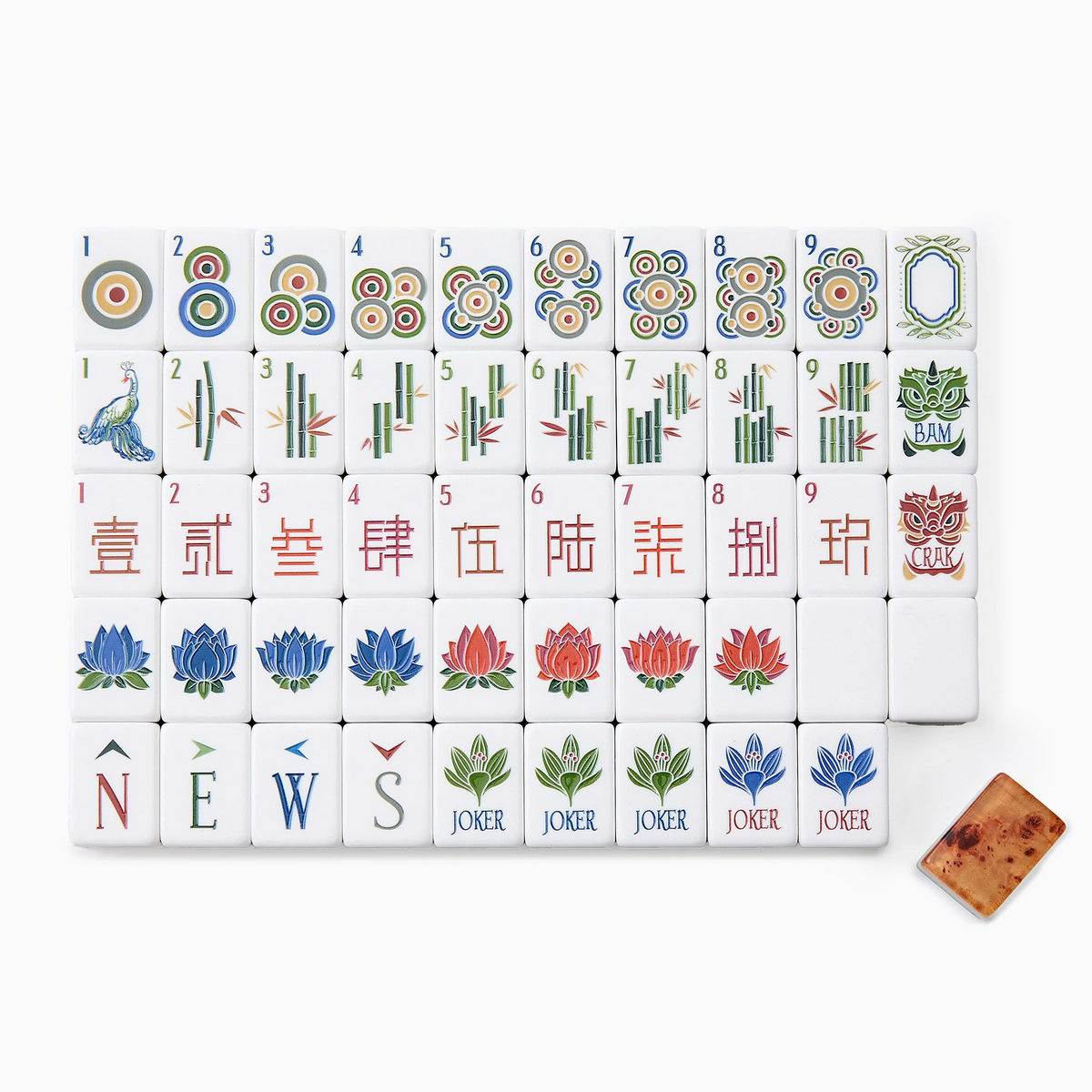 A complete Mahjong Tiles Set - Heritage by Oh My Mahjong is beautifully arranged, featuring circles, bamboo, characters, winds, dragons, flowers, jokers, and a blank tile—all with an heirloom-quality finish—and accented by a brown die in the corner.