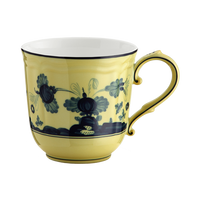 The Oriente Italiano Dinnerware Citrino teacup by Ginori 1735 is a yellow Italian porcelain cup with a curved handle, dark blue chinoiserie floral motifs and ornamental patterns on the exterior, and a plain white interior.