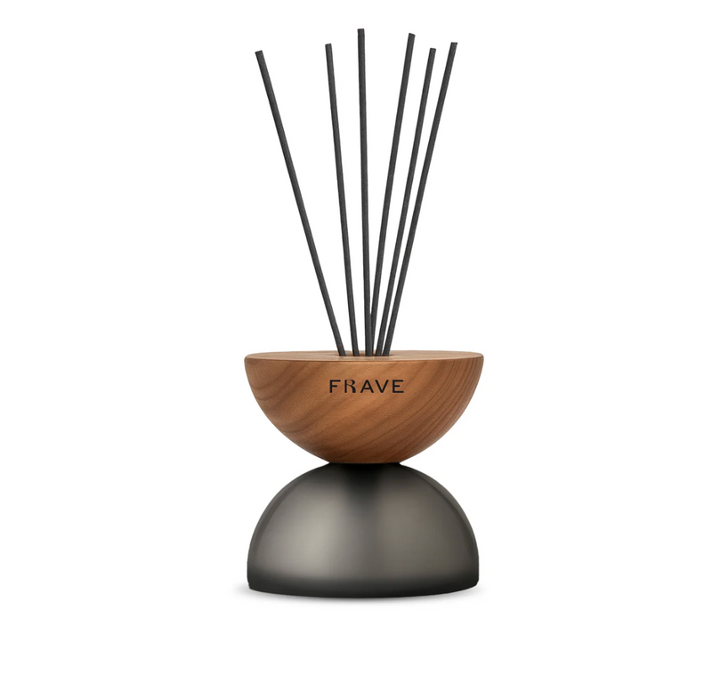 The Breath Wood Frosted Glass Diffuser - Prosecco by Frave Home features a rounded walnut wood top, dark domed base, and black reed sticks—perfect for enjoying a refreshing Prosecco scent.