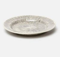 The Nolan Dinnerware Black Cream by Blue Pheasant is a shallow white ceramic bowl with a dark gray radial line pattern, ideal for enhancing your artisanal dinnerware or stoneware collection.
