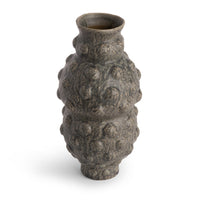 The Tobias Vase by FlowDecor Inc. is a tall, contemporary piece featuring a bumpy, irregular texture, narrow neck, and a mottled dark gray finish.