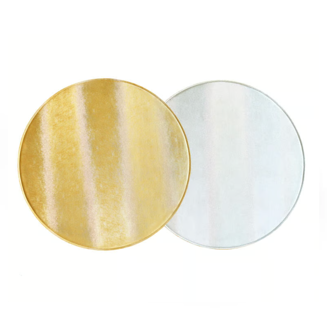 Two round plates—gold on the left, silver on the right—shine atop Von Gern Home's Textured Metallic Reversible Placemat Set of 4, creating a chic, contemporary table setting.