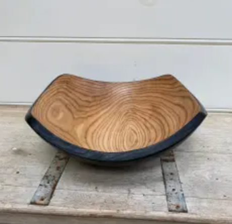 The Peterman Two Toned Square Oak Wood Bowl features a square rim, rounded edges, natural oak grain, and a dark outer edge. Food safe and beautifully presented on rustic wood—perfect for stylish serving.