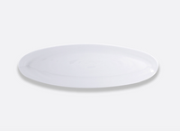 A glossy white oval plate from Bernardaud Origine Dinnerware is centered on a light gray background.