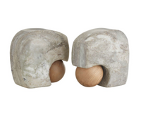 A pair of Arteriors Melt Bookends Set of 2, crafted from mottled gray stone and featuring a wooden sphere partly nestled within each hollowed form, are displayed facing one another against a plain white background. These distinctive bookends seamlessly blend natural textures for an artful accent on any shelf.