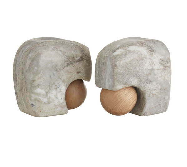 A pair of Arteriors Melt Bookends Set of 2, crafted from mottled gray stone and featuring a wooden sphere partly nestled within each hollowed form, are displayed facing one another against a plain white background. These distinctive bookends seamlessly blend natural textures for an artful accent on any shelf.