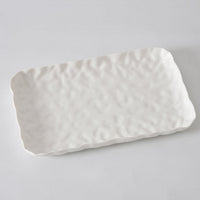 The Willow White Platter Rectangle by PAMPA BAY is a white porcelain tray with a wavy, textured surface and slightly irregular edges, shown on a light gray background.