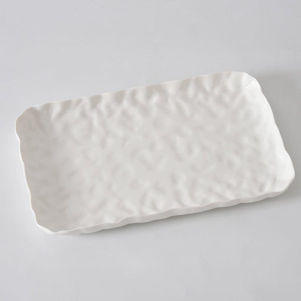 The Willow White Platter Rectangle by PAMPA BAY is a white porcelain tray with a wavy, textured surface and slightly irregular edges, shown on a light gray background.