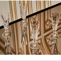 Four Queen’s Hall Champagne Flute- Set of 4 glasses featuring intricate cut patterns, standing on a reflective surface.
