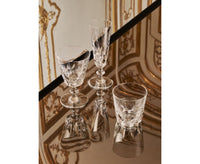 Two ornate Queen’s Hall Champagne Flute glasses and a short cut-crystal tumbler arranged on a reflective surface.