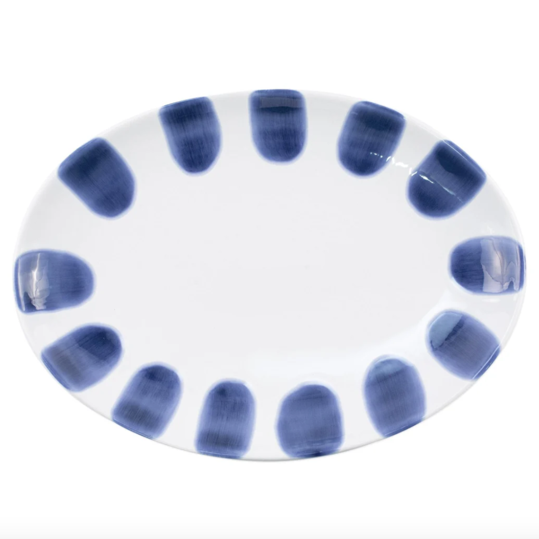 The Vietri Santorini Dot Small Oval Platter is a white ceramic dish accented with broad, evenly spaced dark blue brushstrokes around the rim, inspired by classic Greek Isles design.