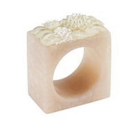 The Ivory Petal Napkin Ring Set of 4 by Bodrum features square-shaped beige rings with a round opening and elegant floral designs on top, bringing graceful sophistication to your table setting.