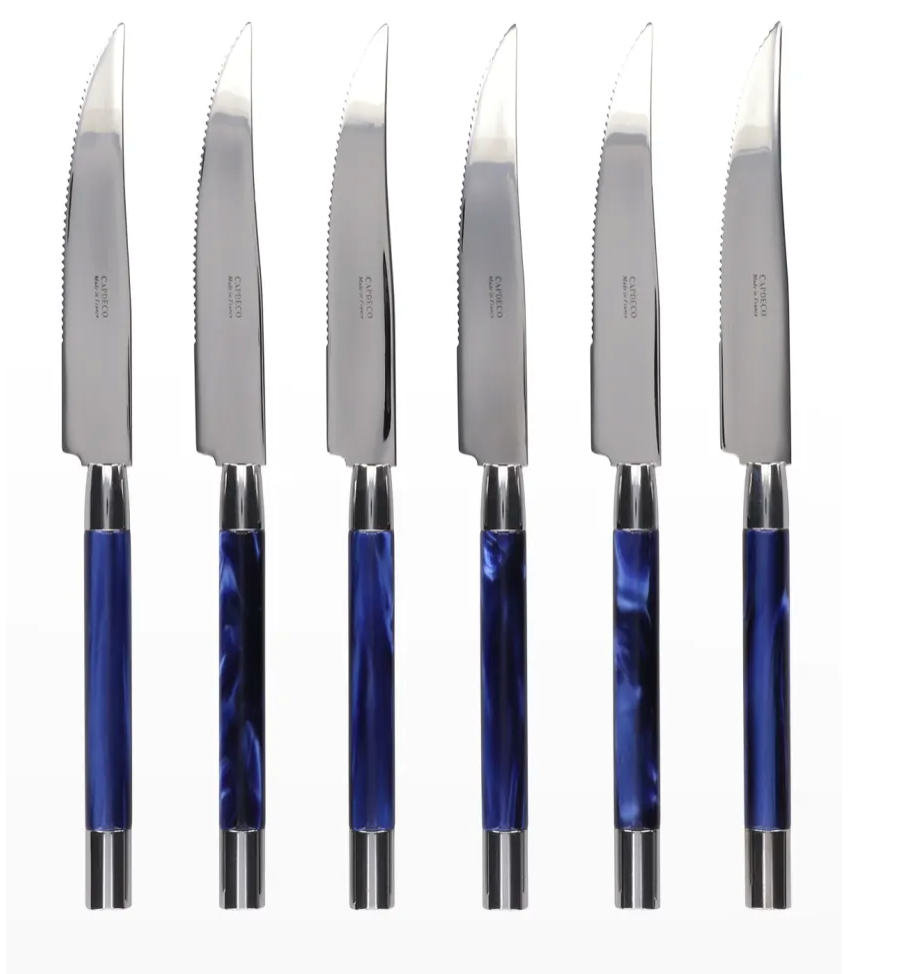 Six Conty Steak Knives by Capdeco, each with shiny silver serrated blades and glossy blue handles with silver accents, are lined up vertically—a stylish French-made set of six shown against a white background.