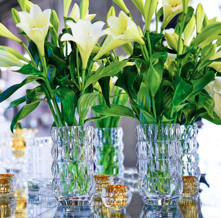 Two clear crystal 11″ Louxor Round Vase 230s with a diamond-cut geometric pattern, each filled with white lily flowers.