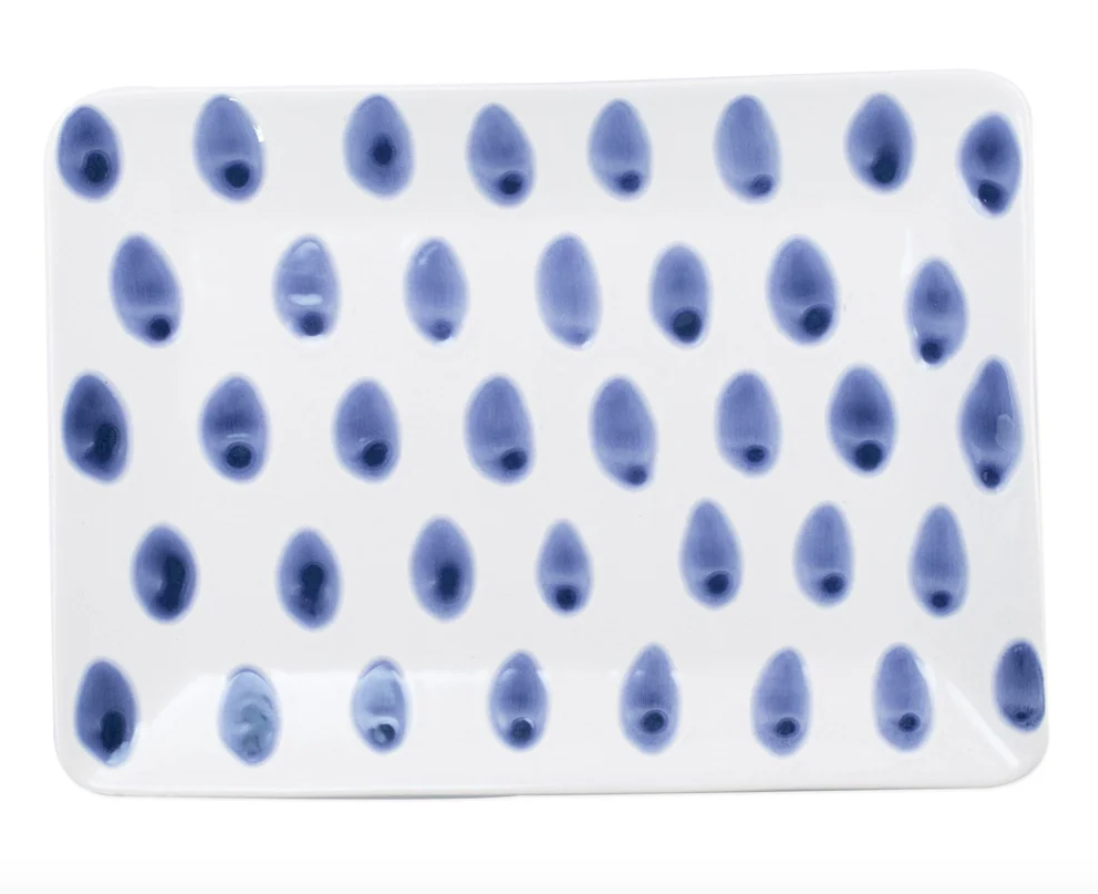 The Vietri Santorini Dot Small Rectangle Platter is a white ceramic tray adorned with blue oval dots in rows, bringing Greek Isles charm to your kitchen.
