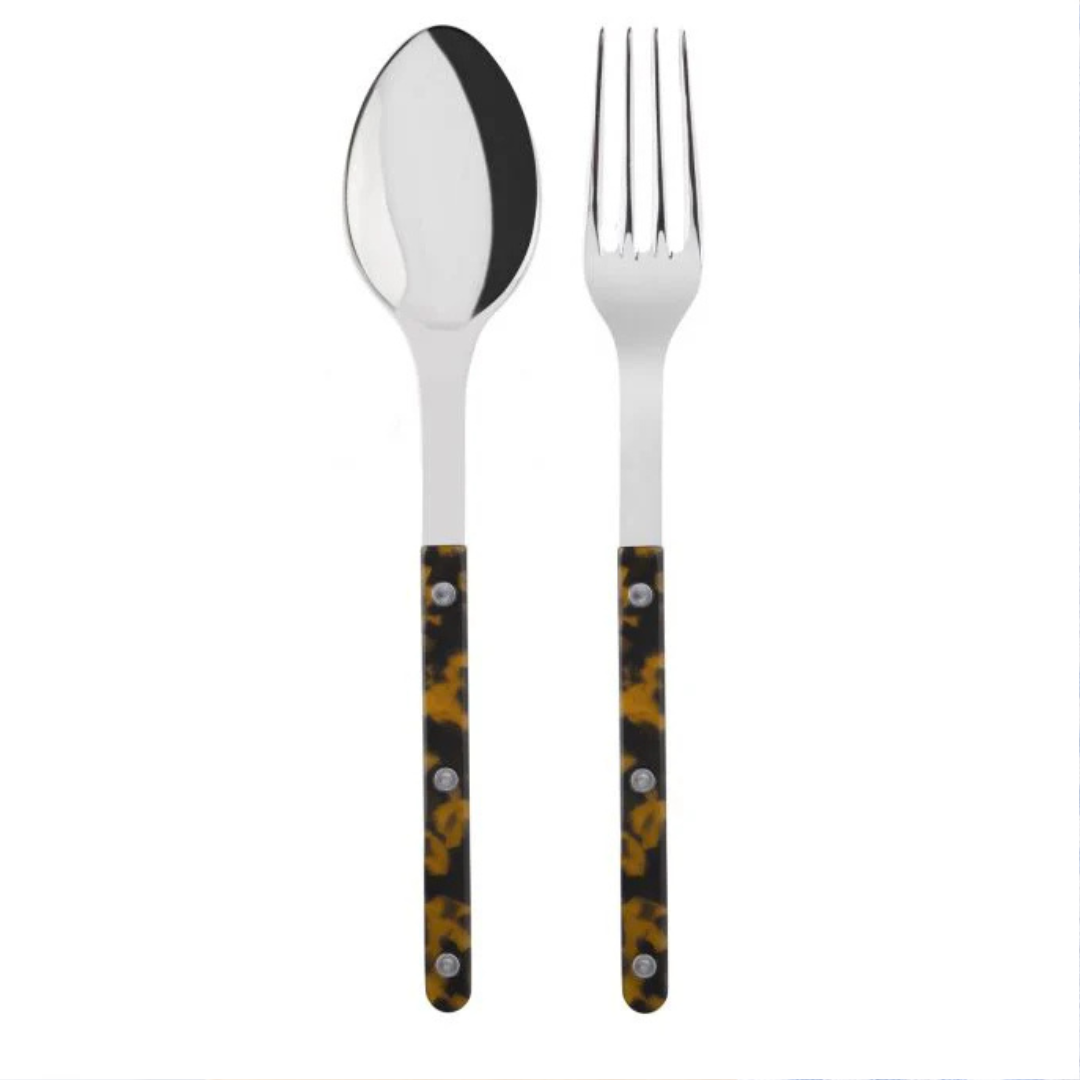 The Sabre Bistrot Shiny Solid Serving Set features a metal spoon and fork with dark handles in a yellow and brown tortoiseshell pattern, accented by three rivets, exuding Parisian flair against a white background.