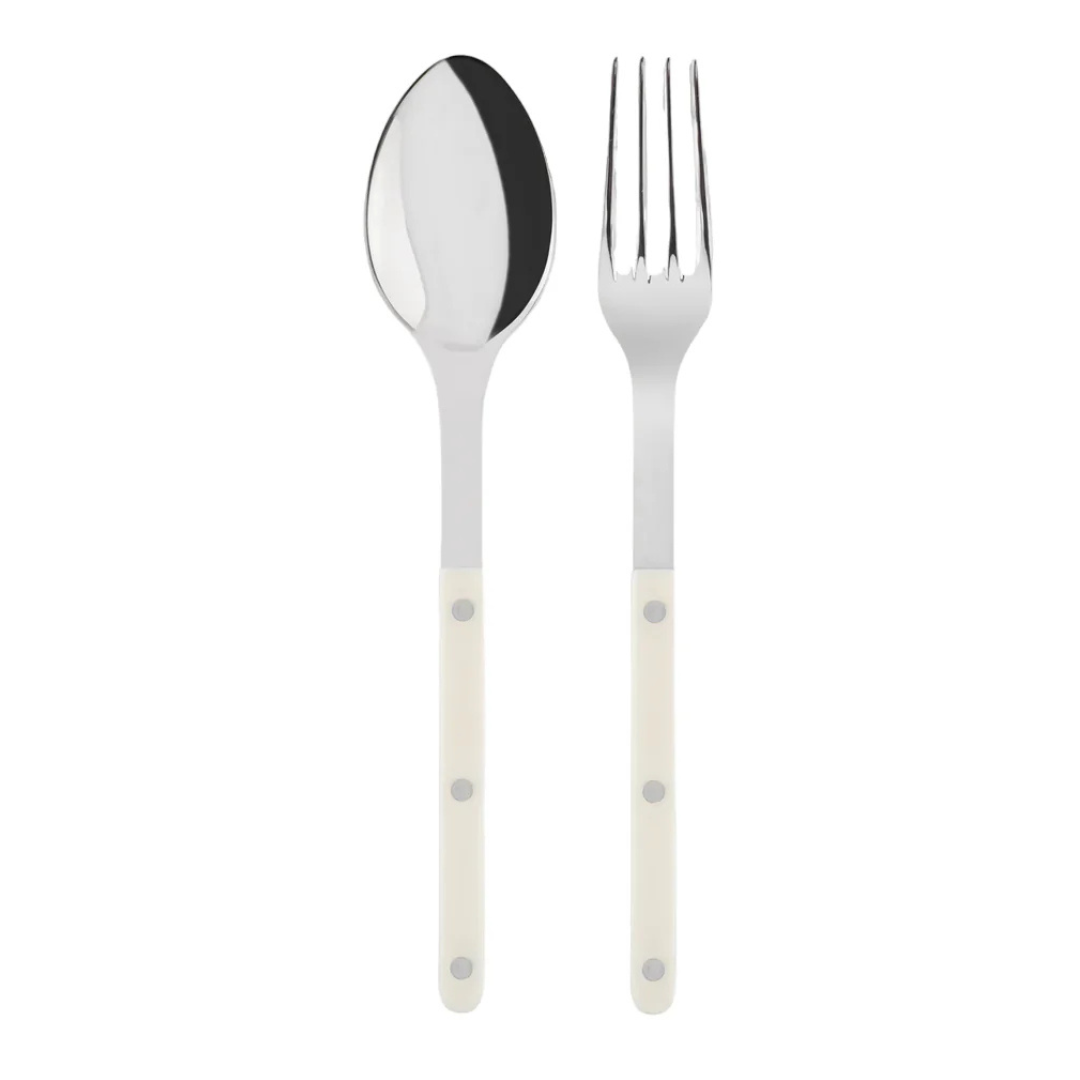 The Sabre Bistrot Shiny Solid Serving Set features a stainless steel spoon and fork with white handles and metal rivets, inspired by Parisian flatware, shown side by side on a plain white background.