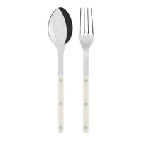 The Sabre Bistrot Shiny Solid Serving Set features a stainless steel spoon and fork with white handles and metal rivets, inspired by Parisian flatware, shown side by side on a plain white background.