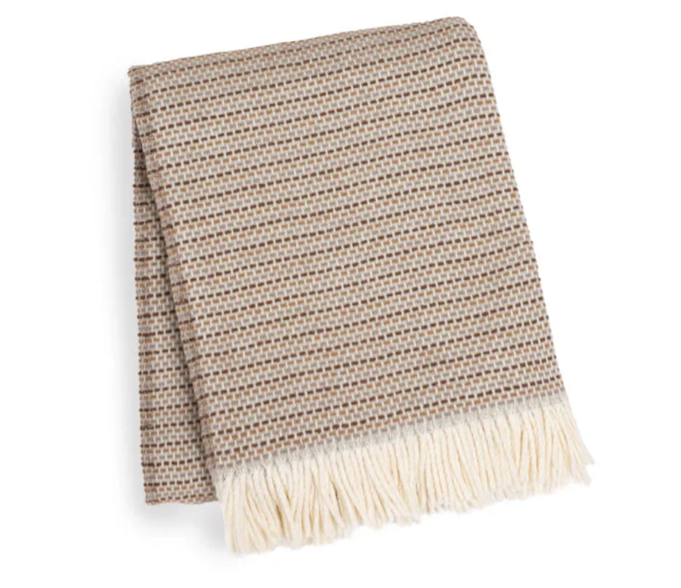 The A Soft Idea Multi Grain of Rice Throw features a beige and brown houndstooth pattern with cream fringe, adding cozy style to your home décor. Shown folded against a white background.
