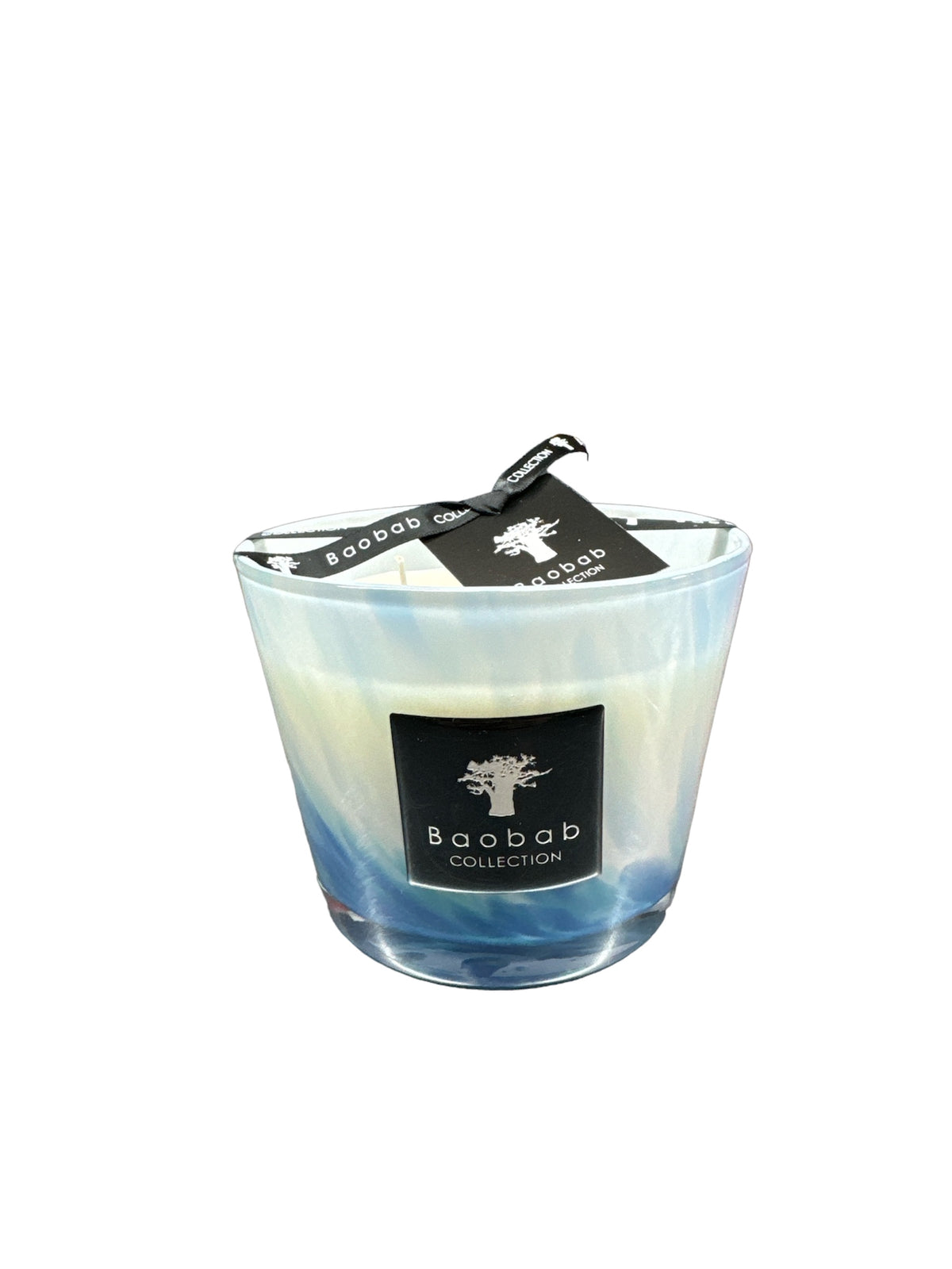 The Baobab Eden Seaside Candle features an opalescent marbled blue and white glass, a black label with a white tree logo, and a black tag on the wick—its fragrance inspired by the South Seas.