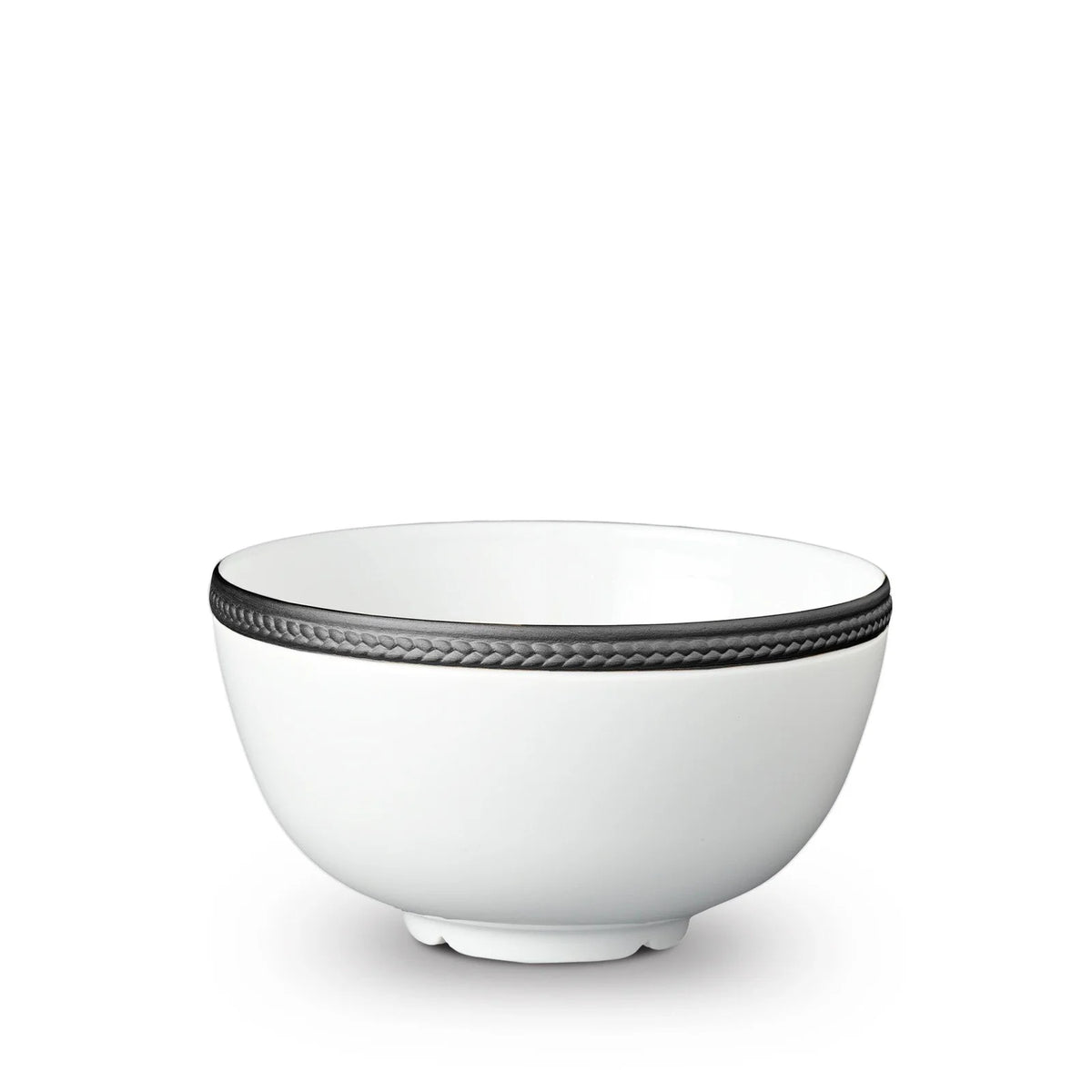 The Soie Tressée Black Dinnerware by L'Objet is a white ceramic bowl with a slightly flared rim, accented by a textured dark gray band around the top and resting on a small, round base.